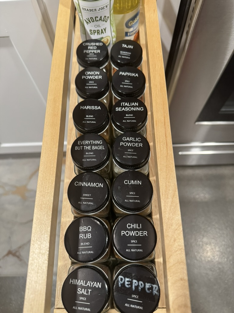 Pull-out spice drawer with labeled jars of cumin, paprika, harissa and more